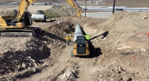 Pipe installation work in progress with an excavator and crew on a sloped trench