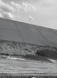 Graded hillside with visible erosion control grid and construction activity below.
